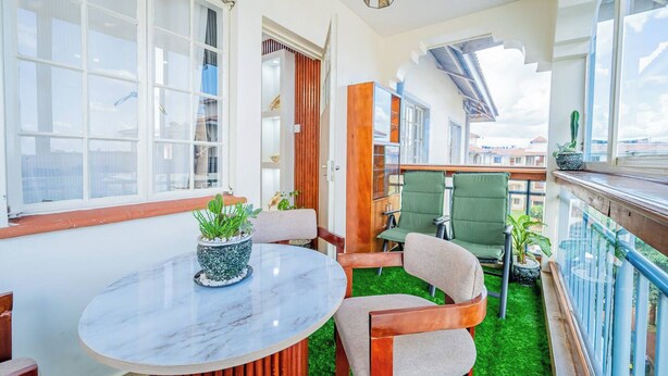 A balcony with a round table, chairs, and potted plants. - Kivulini luxurious and cozy apartment (Thika)