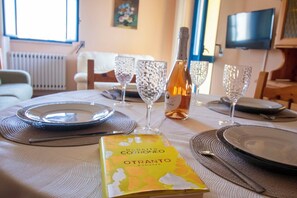 Ein Esstisch mit Geschirr, Gläsern und einer Weinflasche, darauf liegt ein Buch mit dem Titel 'Roberto Cortroneo Otranto'.