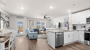 Une cuisine moderne avec des meubles blancs, un îlot central et un coin repas comprenant une table et des chaises.