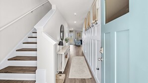 Un couloir avec un escalier, une console sur laquelle est posée une lampe, un miroir et une porte dotée d’une serrure.