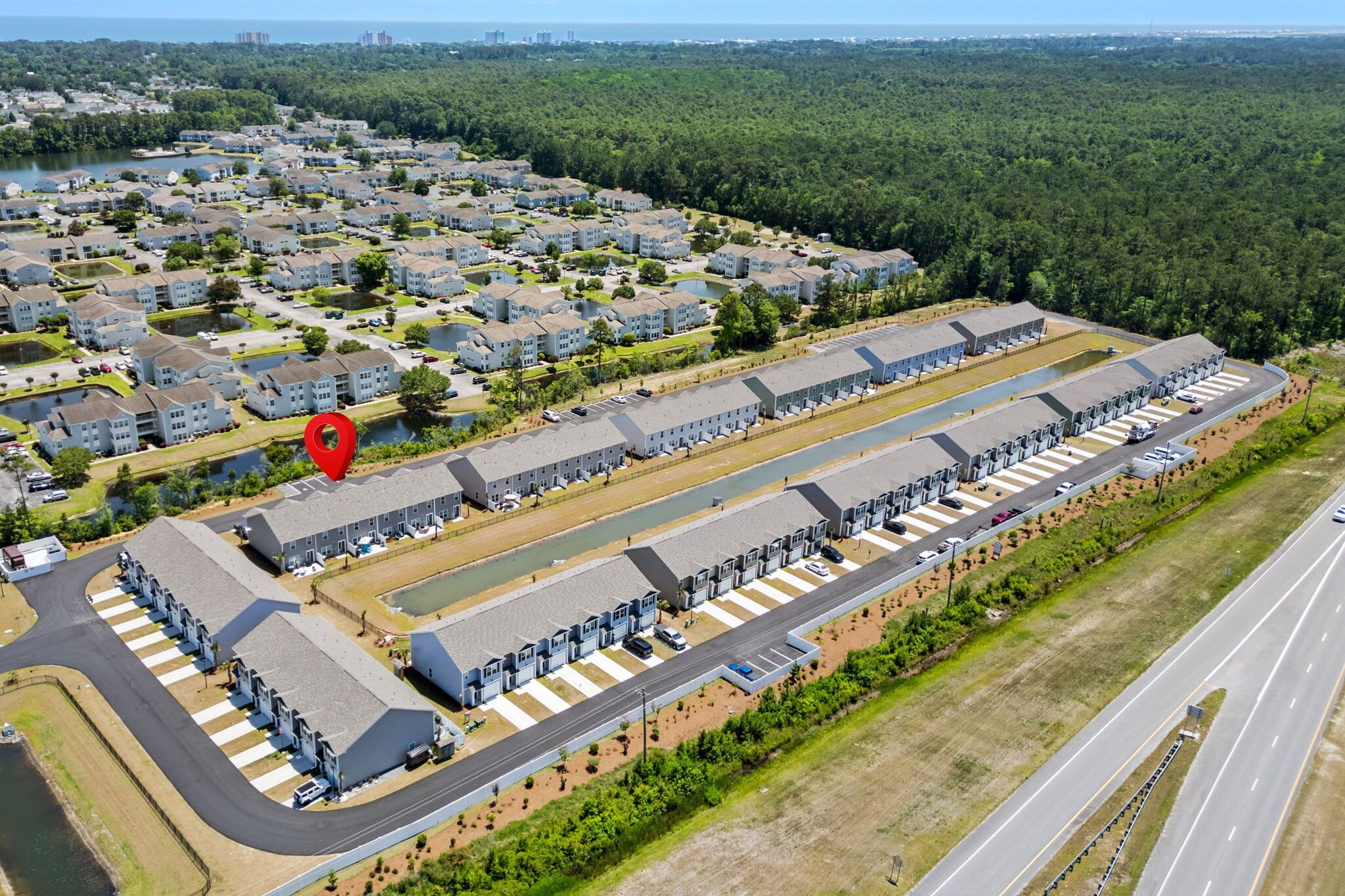 An aerial view of a residential area with apartment buildings, a parking lot, and a road.
