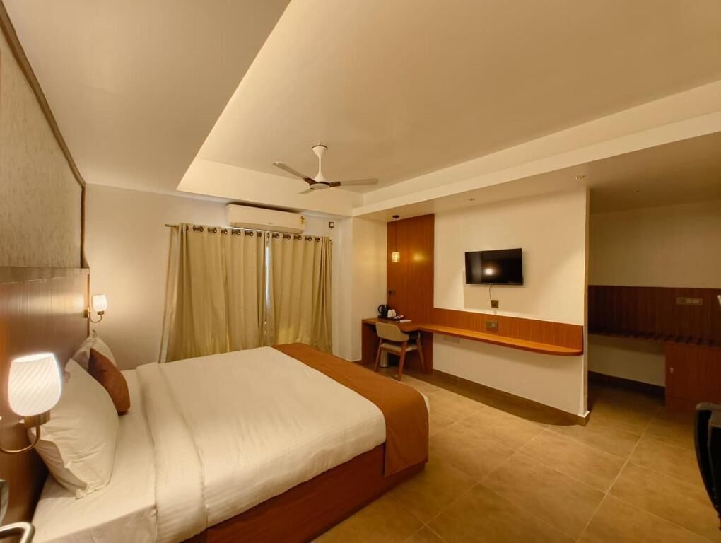 A hotel room with a bed, desk, chair, television, and a ceiling fan.