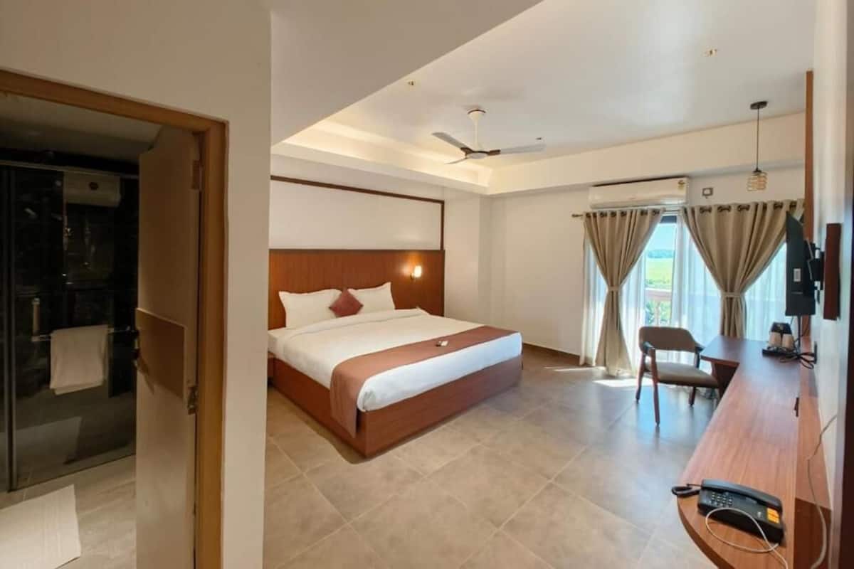 Una habitación de hotel con cama, escritorio, silla y baño con ducha.