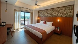 Habitación de hotel con cama, escritorio, teléfono, lámpara de pared y vistas al exterior.