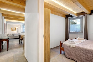 A room with a bed, a window, a wooden ceiling, and a sofa in the background. - Apartment '3' with Private Parking, Shared Garden, Central Morgex Location (Morgex)