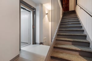 Eine Treppe mit Handlauf, eine Tür mit Schiebeglasfenster und eine wandmontierte Leuchte.