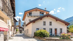A street with a building featuring a balcony, a bell tower, and a mountain in the background. - Apartment '5' with Two Balconies, Private Parking and Shared Garden (Morgex)