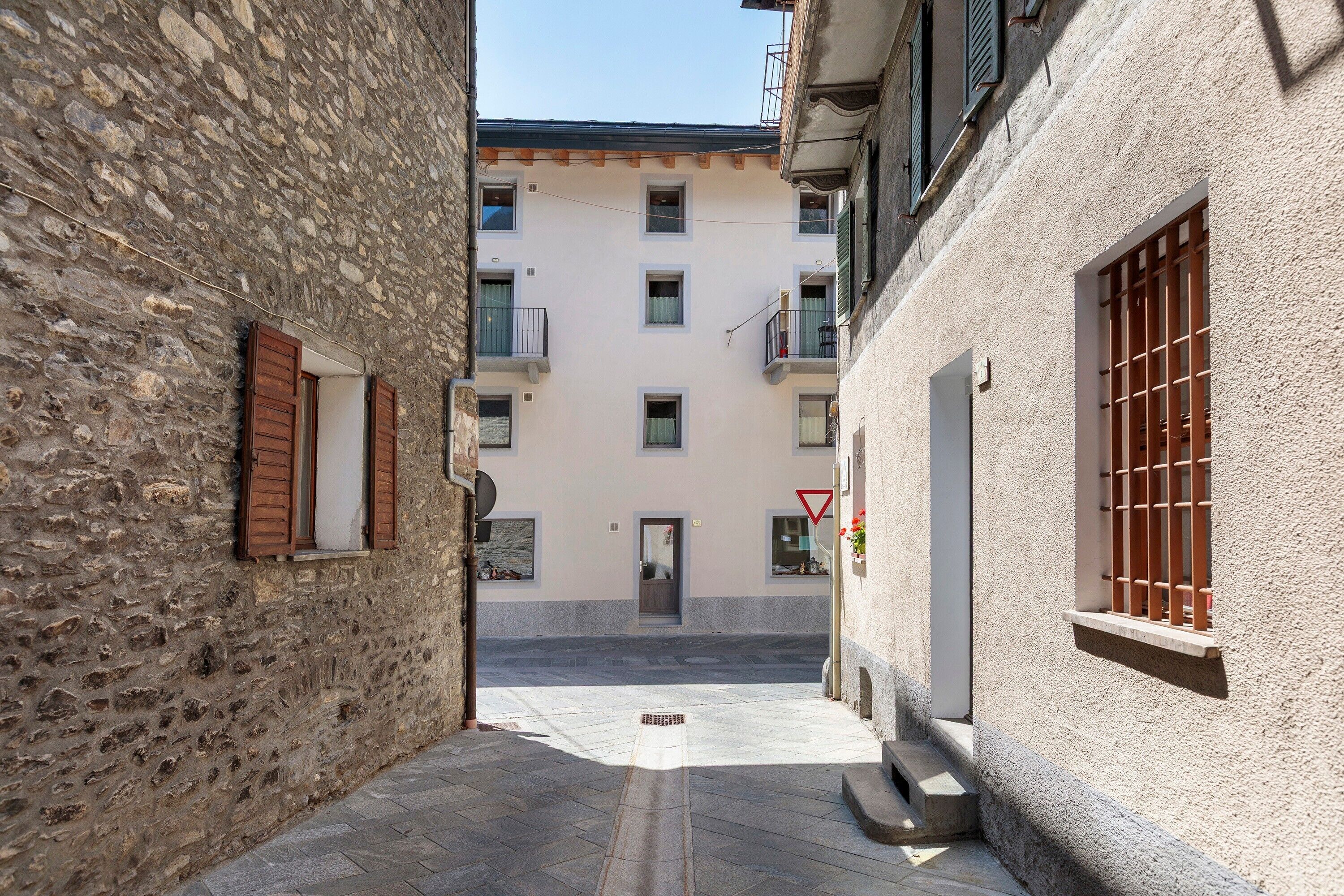 A narrow street with stone buildings, a visible door, and a red traffic sign.
