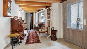 A room with a piano, a wooden chair, a red rug, and a large window with a view. - Apartment '5' with Two Balconies, Private Parking and Shared Garden (Morgex)