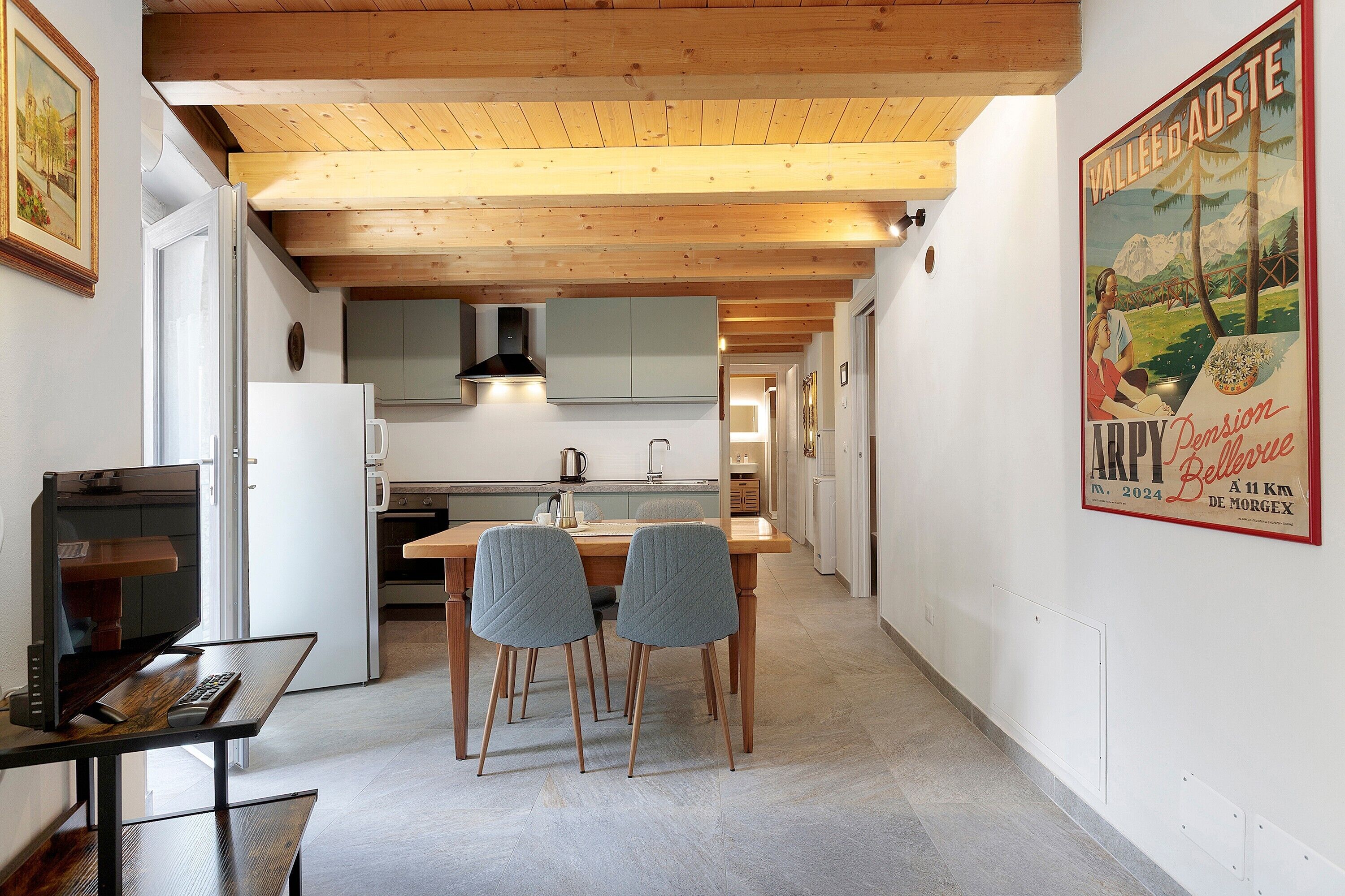Une cuisine moderne avec des poutres en bois, un coin repas avec deux chaises et une affiche accrochée au mur.