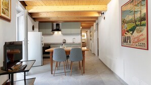 A modern kitchen with wooden beams, a dining area with two chairs, and a poster on the wall. - Apartment '5' with Two Balconies, Private Parking and Shared Garden (Morgex)
