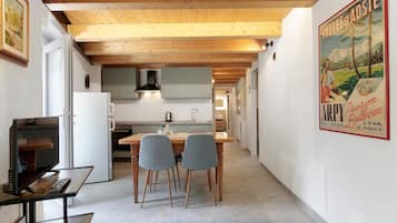Une cuisine moderne avec des poutres en bois, un coin repas avec deux chaises et une affiche accrochée au mur.