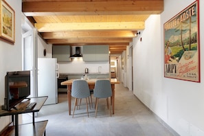 Eine moderne Küche mit Holzbalken, einem Essbereich mit zwei Stühlen und einem Poster an der Wand.