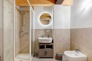 Une salle de bain équipée d’une douche, d’un lavabo, d’un bidet et d’un miroir.