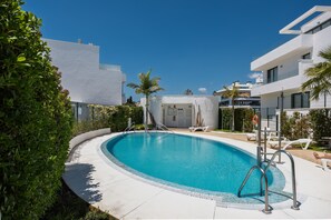 A modern swimming pool with a curved edge, surrounded by white buildings and greenery. - AS EXT Fgrl OAK 47 - 38 (Fuengirola)