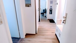 Ein Flur mit Holzboden, weißen Wänden und einer Tür zu einem Zimmer.