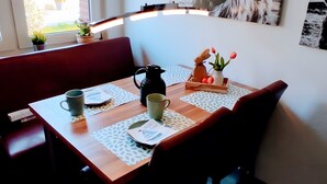 Ein Esstisch mit einer Kanne, Tassen und einer Schale mit Blumen und Tomaten.