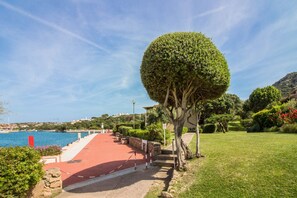 Ein Küstenweg mit rotem Verlauf, einer gepflegten Hecke und Blick aufs Meer.