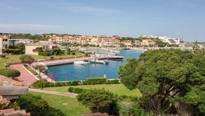 A coastal town with a marina, buildings, and greenery. - GuestHost - Porto Cervo Spacious Flat by the Port (Arzachena)