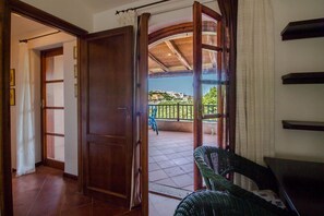 Ein Zimmer mit einer Holztür, die auf einen Balkon mit Blick auf Gebäude und Grünflächen führt.