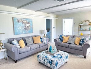 Ein Wohnzimmer mit zwei grauen Sofas, einem Couchtisch und einem Bild an der Wand.