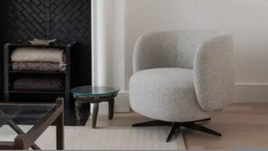 A modern living room with a fireplace, a television mounted on the wall, a grey armchair, and a small round table. - Chelsea White House Retreat 3 Bedroom House (London)