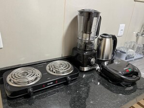 A kitchen with a gas stove, a blender, a kettle, and a microwave. - Ribeiro Flat (Várzea Grande)