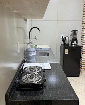 A compact kitchen with a gas stove, a sink, and a coffee maker.