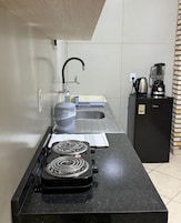 Cozinha compacta com fogão a gás, pia e cafeteira.