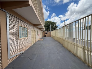 A building with a brick facade, a covered walkway, and a metal fence.