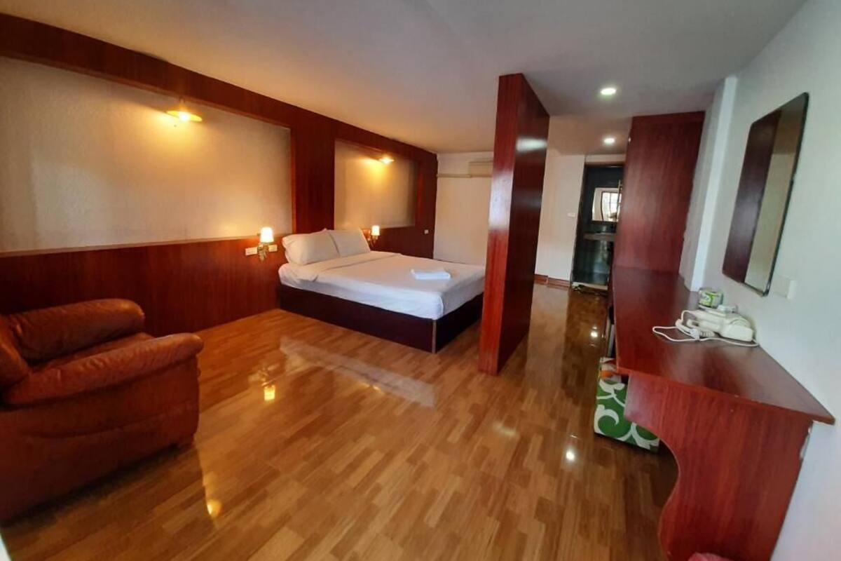 Una habitación de hotel con cama, sofá, escritorio y espejo.