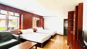 Habitación de hotel con piso de madera, un sofá, una cama, un televisor y un armario de madera.