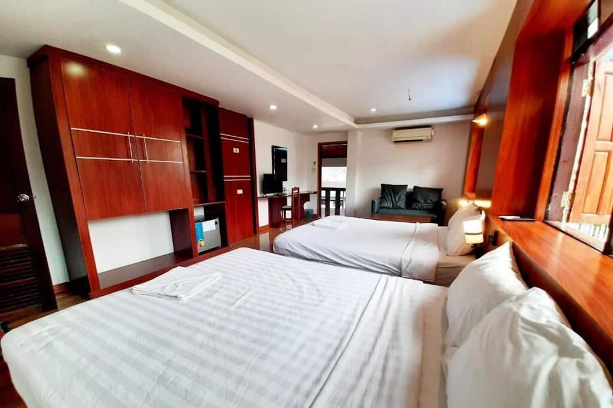 Habitación de hotel con dos camas, televisión, escritorio y armario.