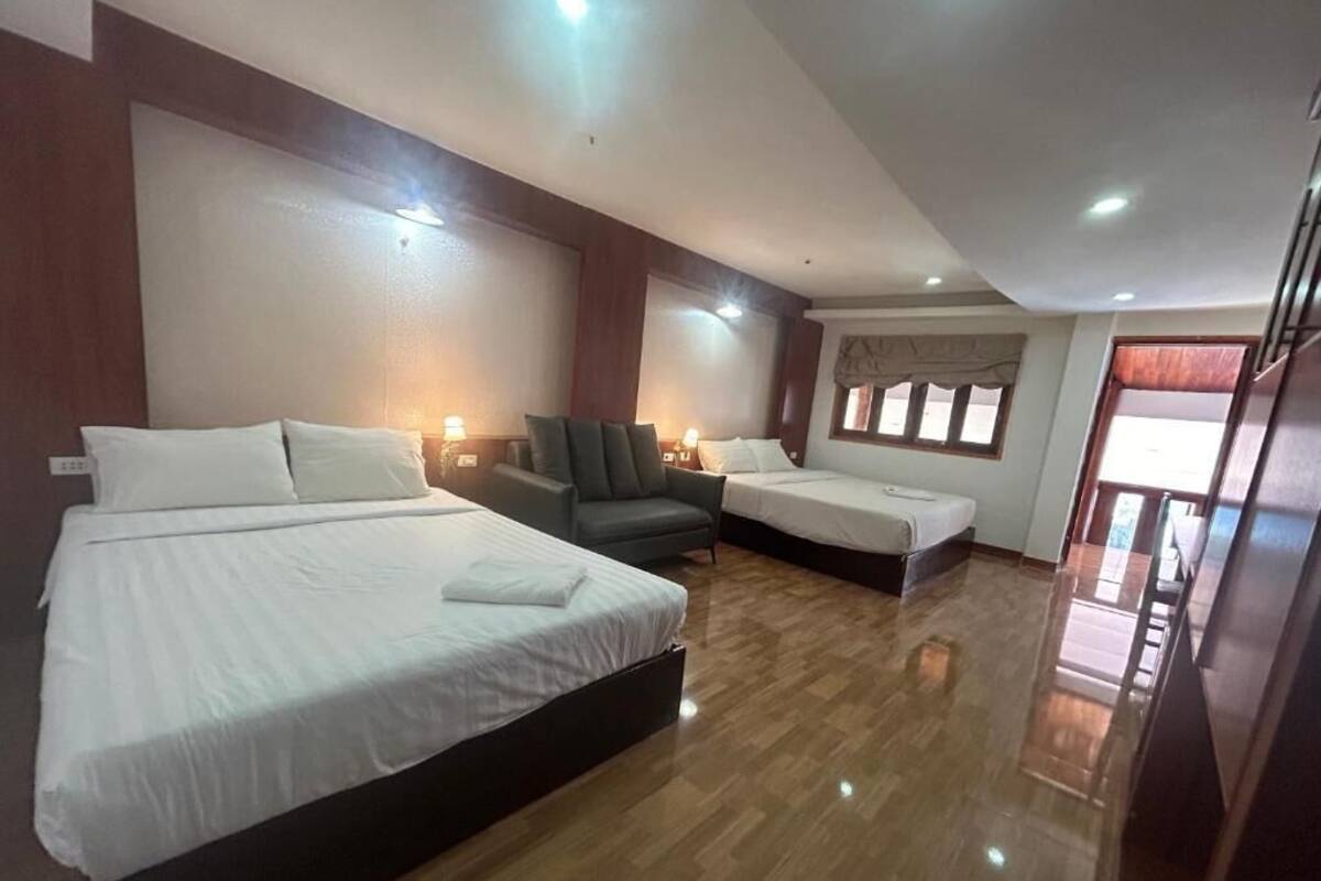 Una habitación de hotel con dos camas, un sofá, un escritorio y una ventana.