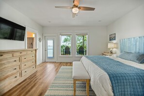 Ein Schlafzimmer mit Bett, Nachttisch, Kommode, Deckenventilator und Blick durch die Tür.