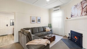 Ett vardagsrum med en soffa, en öppen spis och en tavla på väggen.