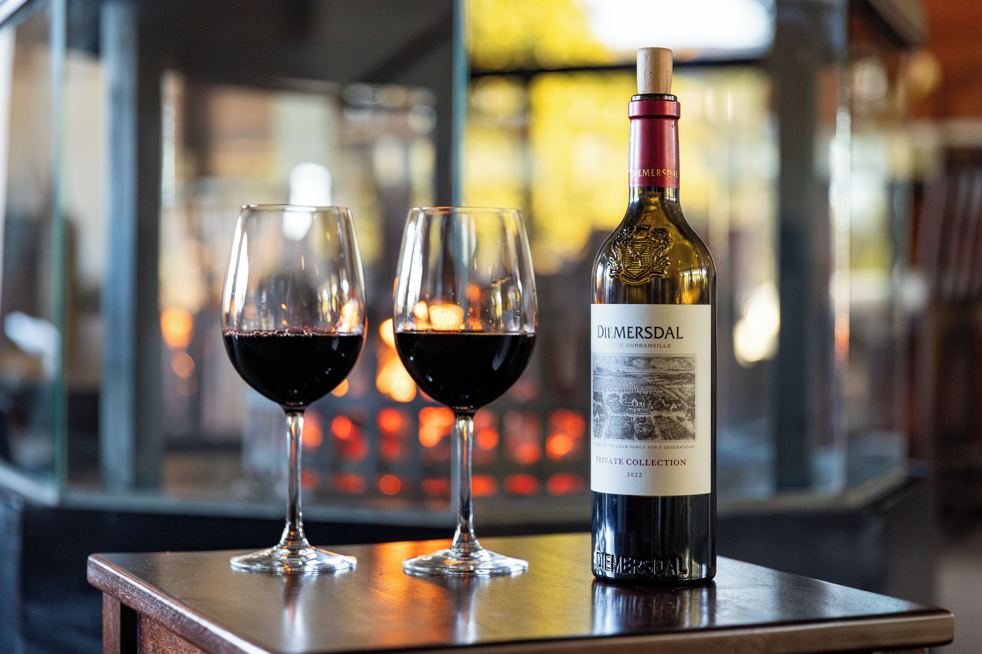 A bottle of wine and two glasses on a table with a blurred background.
