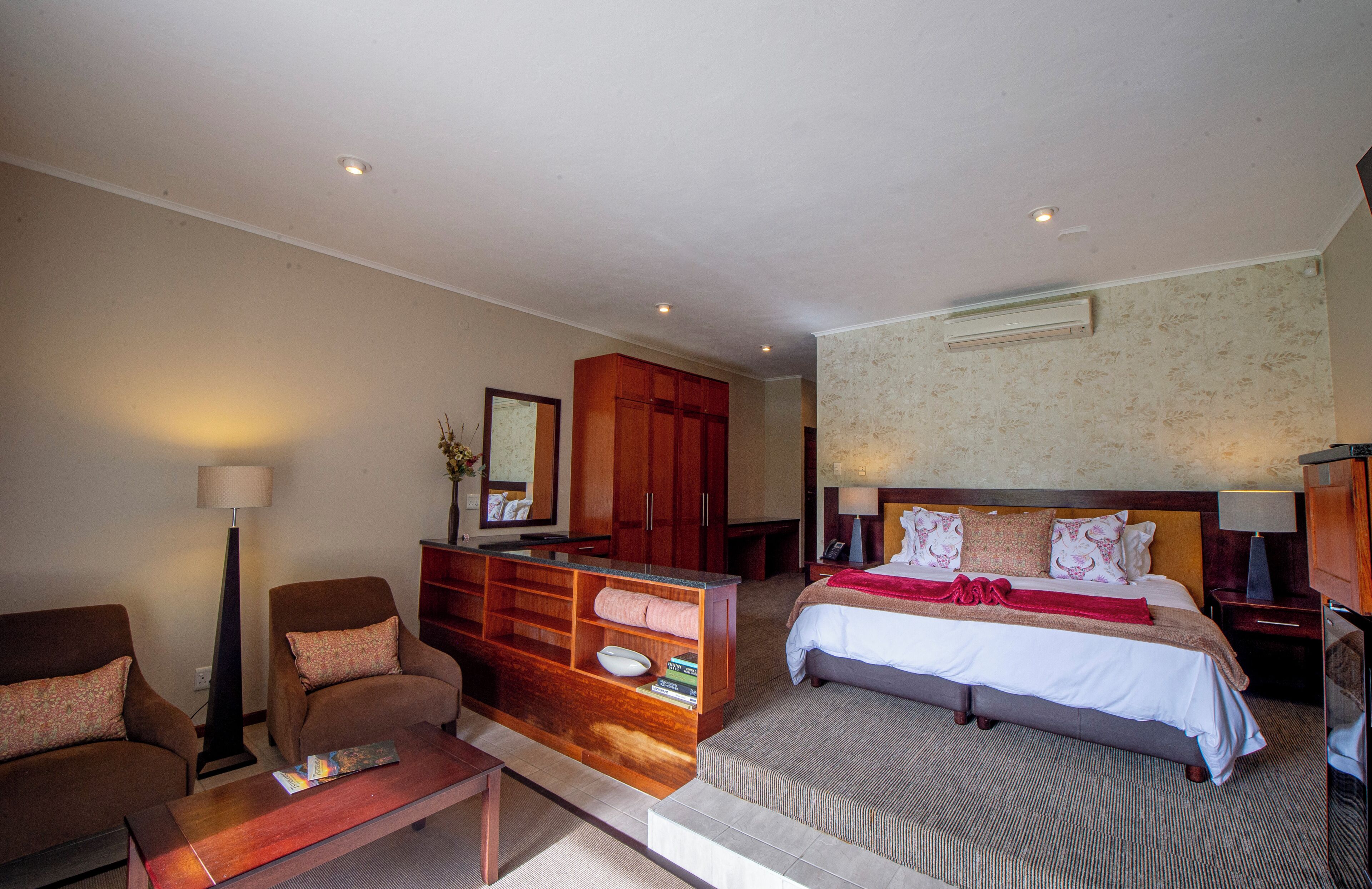 Ein Hotelzimmer mit Bett, Sofa, Schreibtisch, Kleiderschrank und Spiegel.