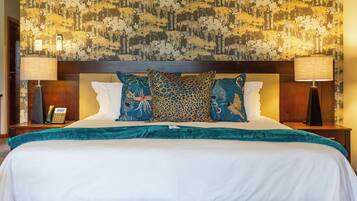 A hotel room with a large bed, two bedside lamps, a telephone, and a patterned wallpaper.
