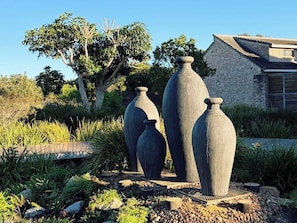Large stone vases in a garden with a house in the background. - Plateau Country House (Nature's Valley)
