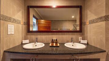 Un baño con dos lavamanos, un espejo grande y un mueble de tocador de madera.