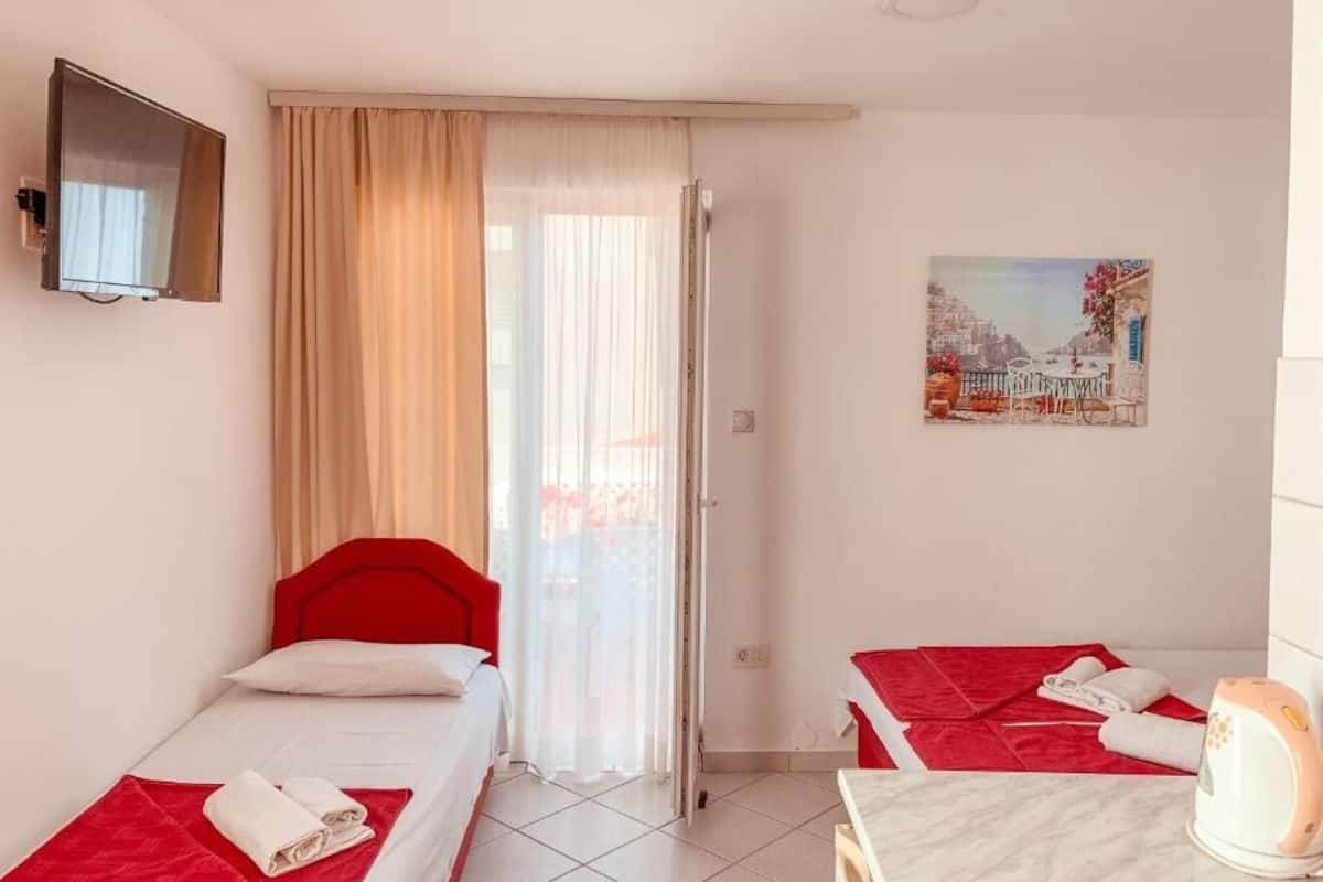 Ein Hotelzimmer mit zwei Betten, einem Fernseher, einem Gemälde und einem Wasserkocher.