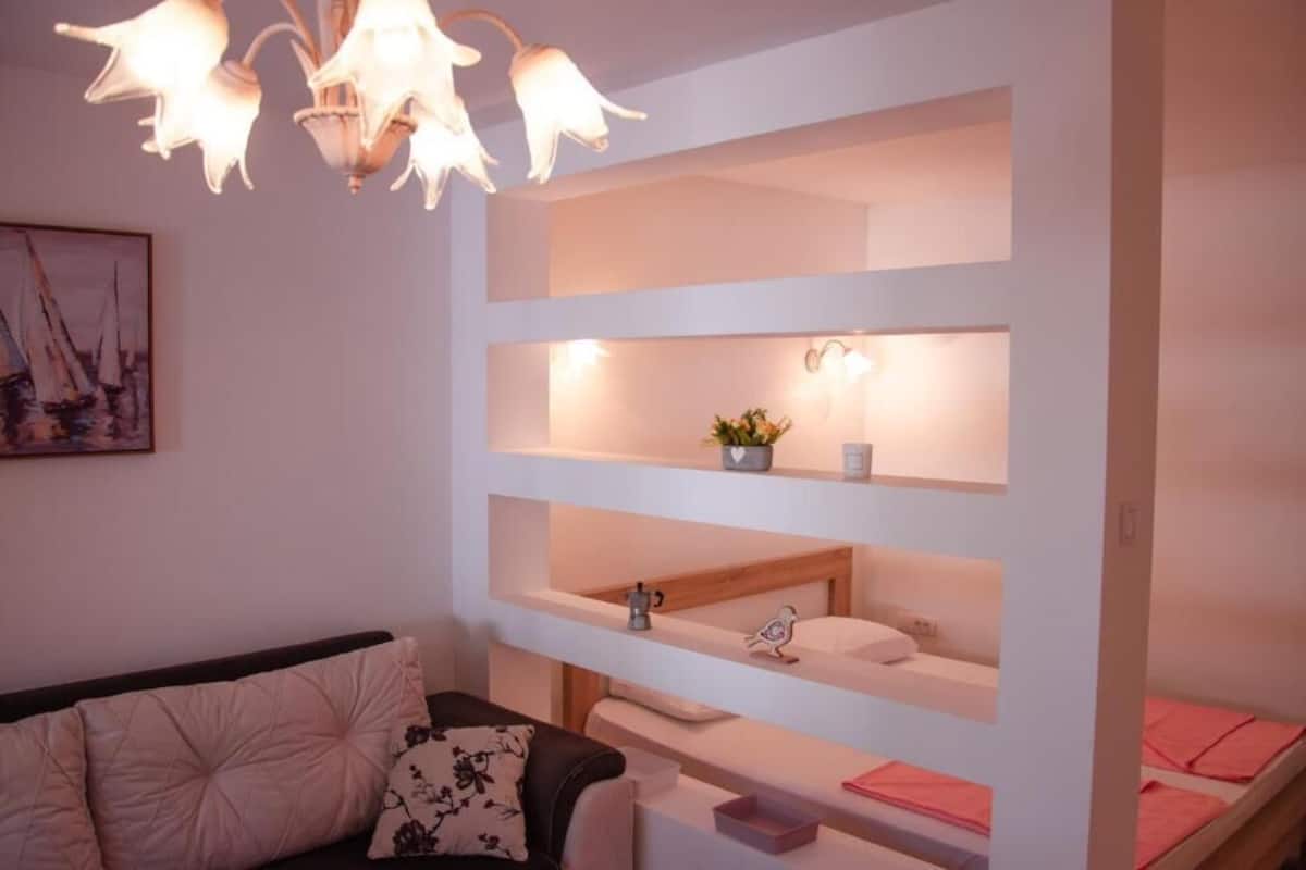 Ein Zimmer mit einem Etagenbett, einem Nachttisch, einer Lampe, einem Gemälde und einem Sofa.