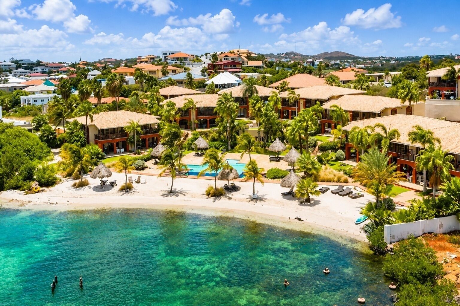 A resort with a beachfront, pool, and palm trees.
