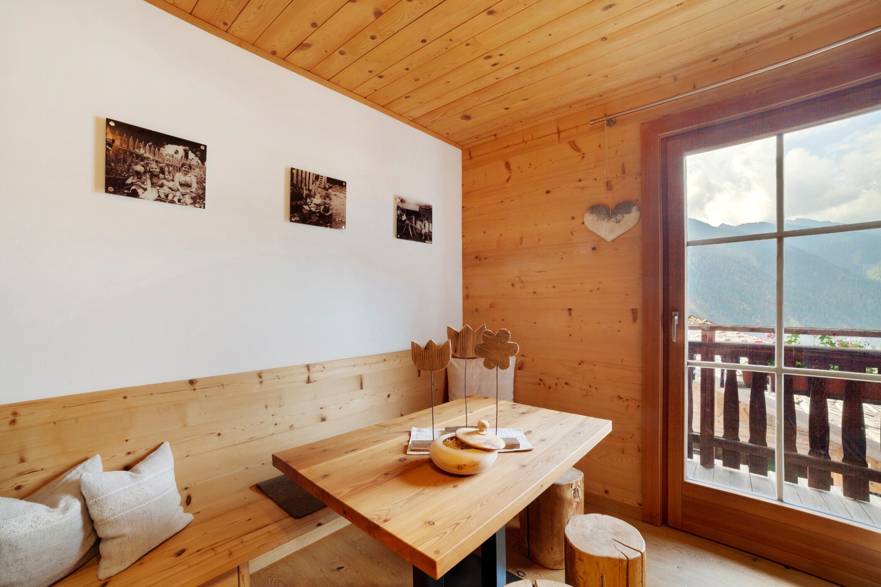 A wooden interior with a table, benches, and a window with a mountain view.