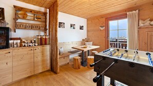 A wooden-floored room with a foosball table, wooden cabinets, a bench, and a window with a view. - Apartment 'Schwalbennest' with Mountain View, Shared Garden and Wi-Fi (Durago di Dentro)