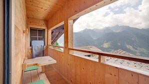 A wooden cabin with a balcony, a small table, and a view of mountains. - Apartment 'Schwalbennest' with Mountain View, Shared Garden and Wi-Fi (Durago di Dentro)