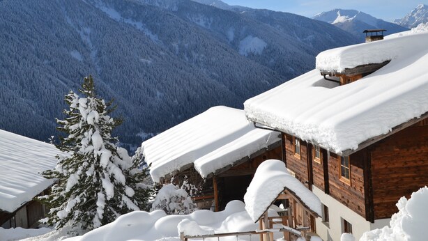 A wooden cabin with snow-covered roofs and a mountain backdrop. - Apartment 'Schwalbennest' with Mountain View, Shared Garden and Wi-Fi (Durago di Dentro)