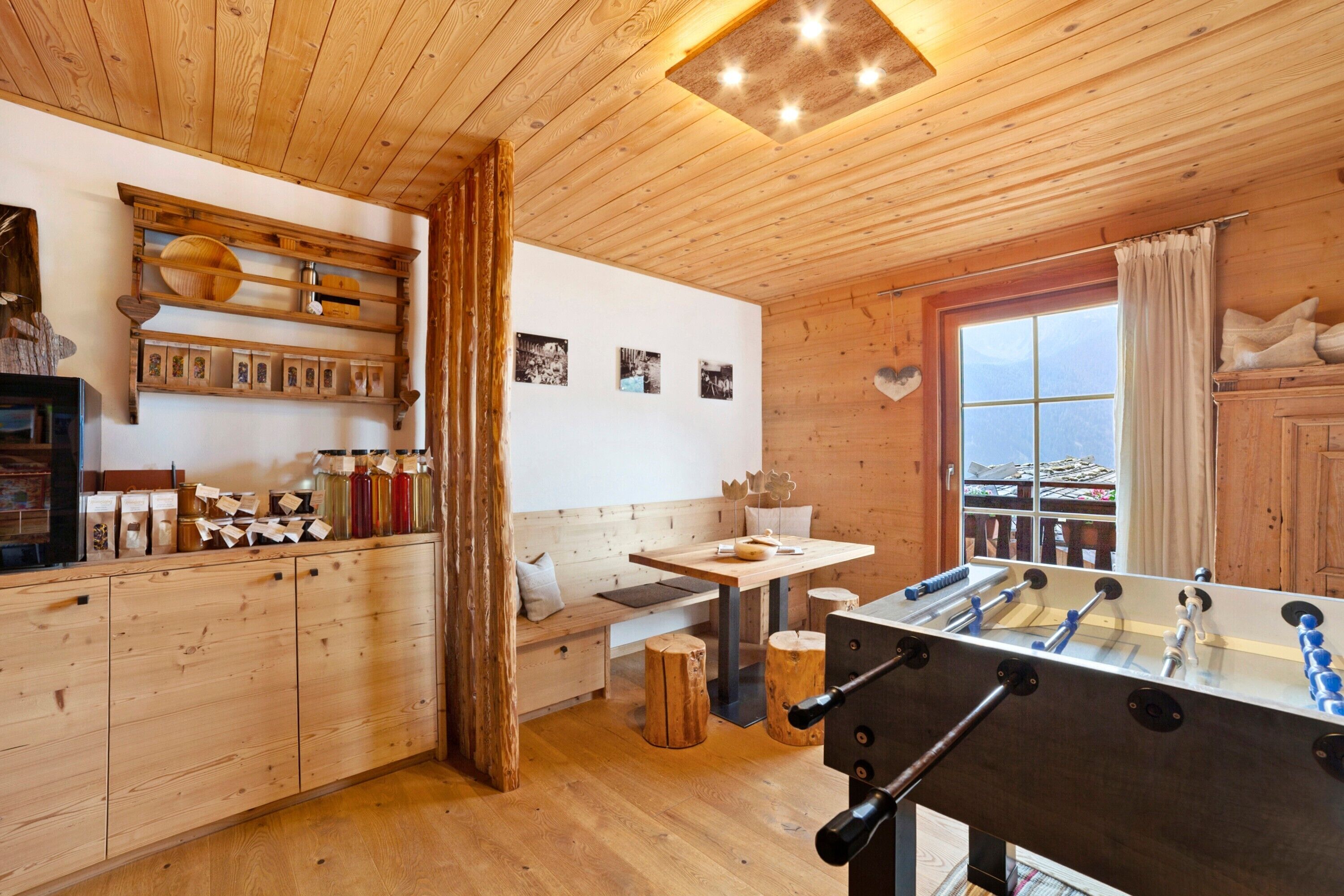 Ein Zimmer mit Holzboden, einem Kicker, Holzschränken, einer Bank und einem Fenster mit Blick.