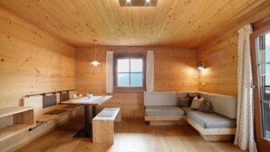 Een houten cabin met een bank, een tafel en een raam met gordijnen.